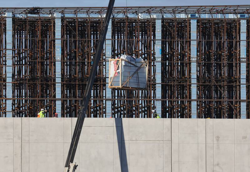 A large crane lifts materials to construction workers at the site of the Kraft Heinz Company distribution center Wednesday, Dec. 13, 2023, in the ChicagoWest Business Center in DeKalb.